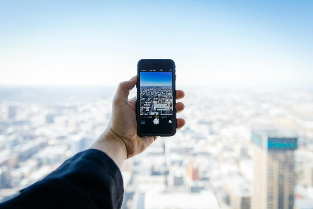 man's hand holding an iphone in front of a the city sky